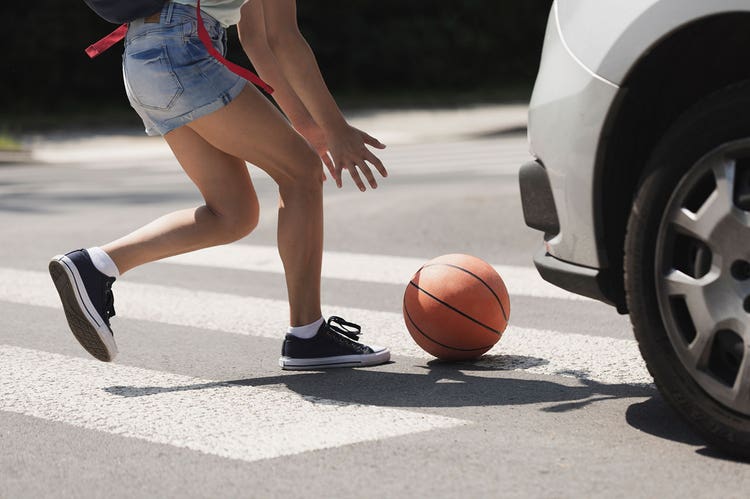 Child jumps in front of a car at a crosswalk to catch a basketball