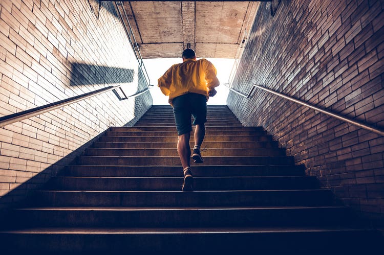 Person wearing a yellow jacket running up a flight of stairs