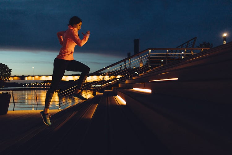 Person running up stairs at night in an urban park