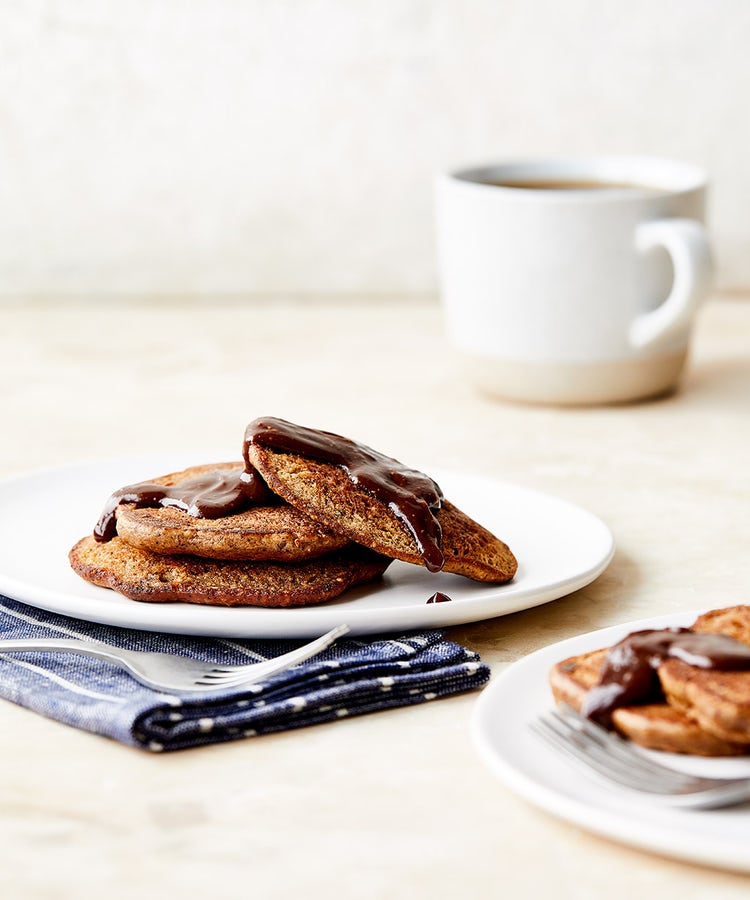 Two plates of chocolate pancakes and a mug