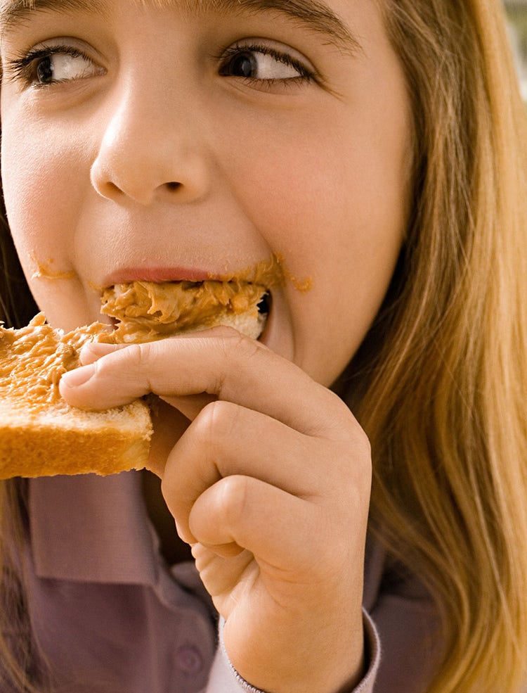 Closeup of child eating a slice of toast with nut butter