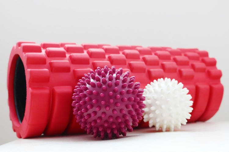 An assortment of pink and white foam rollers and massage balls