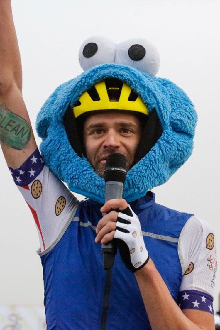 Phil Gaimon gives a speech while wearing a cookie monster mask over his helmet